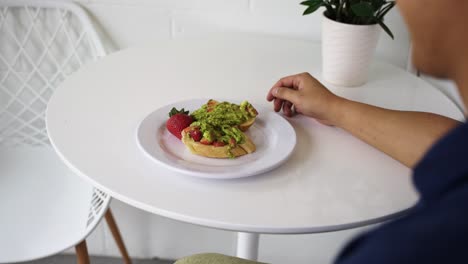 Avocado-Toast-Und-Erdbeerfrühstück-Auf-Einem-Weißen-Tisch,-Kameraschwenk-Von-Links-Nach-Rechts