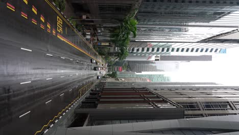 Vertical-video---Raining-day-scene-of-the-street-with-moving-traffic,-highrise-skyscraper-office-financial-building-tower-in-the-Central-Business-District,-Robinson-Road,-Singapore