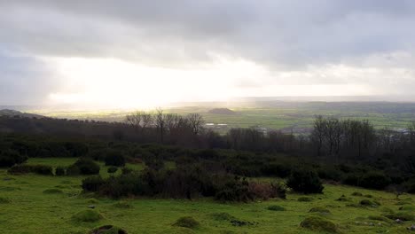 Sunlight-through-rain-clouds-over-English-pasture-farmland-landscape-view-from-Cheddar-Gorge-in-Sedgemoor-district-of-Somerset,-Southwest-of-England