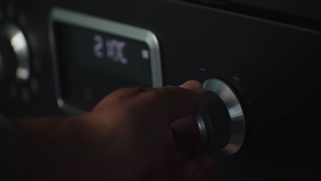 Person-hand-rising-temperature-of-oven-using-knob,-close-up-view