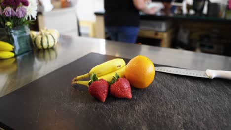 fruits-and-a-knife-on-a-cutting-board-with-the-camera-panning-out-slowly-in-a-restaurant