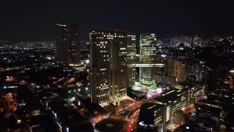 Aerial-view-around-the-illuminated-Arcos-Bosques-shopping-complex,-night-in-Mexico-city