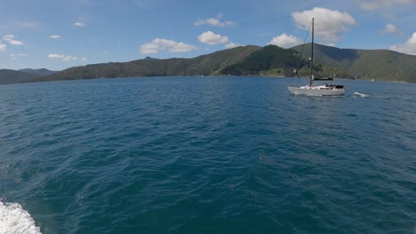Wide-angle-view-of-passing-yacht,-beautiful-blue-water-and-vast-landscape-in-summertime---Queen-Charlotte-Sound,-New-Zealand