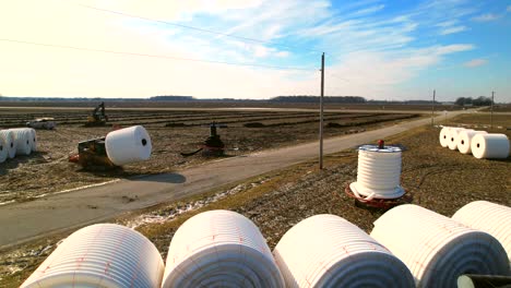 Forklift-handling-large-industrial-coils-with-white-plastic-tubes-in-rural-landscape