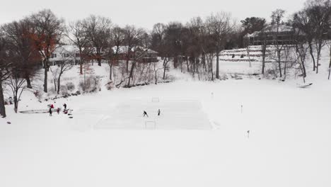 Aerial,-family-and-friends-playing-ice-hockey-on-an-outdoor-ice-rink-made-on-frozen-lake