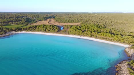 Luftaufnahme-Des-Son-Saura-Strandes-Mit-Klarem-Blauem-Wasser-In-Menorca-Spanien,-Weite-Aufnahme-Verfolgend