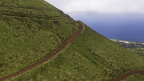 quad-bikes-on-dirt-road-sided-by-lush-green-in-São-Jorge-island,-the-Azores,-Portugal