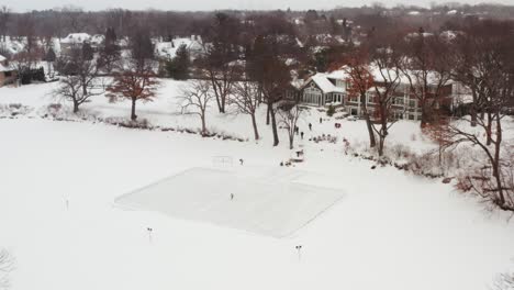 Aerial,-person-skating-with-a-hockey-stick-alone-on-small-homemade-outdoor-ice-rink