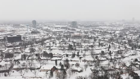 Aerial,-rural-neighborhood-suburb-during-winter,-houses-covered-in-snow