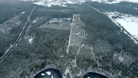 Backwards-drone-dolley-shot-of-nice-scene-of-a-heart-shaped-lake-surrounded-by-forest-in-winter-time