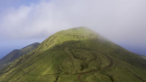Drohne-Umkreist-Den-Vulkanischen-Berg-Pico-Da-Esperança,-Bedeckt-Mit-üppigem-Grün-Mit-Niedrigen-Wolken-Auf-Der-Insel-São-Jorge,-Den-Azoren,-Portugal