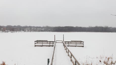 Snow-covered-dock-on-a-frozen-lake-during-winter