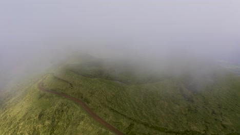 Drone-top-view-of-vulcanic-mountain,-Pico-da-Esperança,-covered-in-lush-green-with-low-clouds-in-São-Jorge-island,-the-Azores,-Portugal