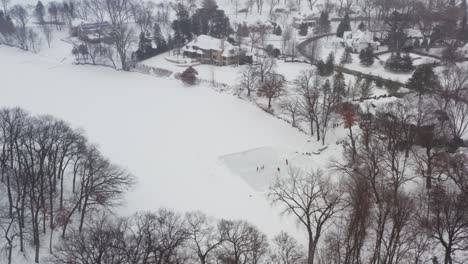 Aerial,-friends-and-family-skating-on-a-homemade-ice-rink-in-backyard-lake-pond
