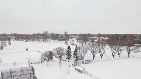 Aerial,-empty-neighborhood-community-park-sports-complex-covered-in-snow-during-winter