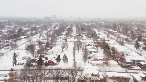 Aerial,-snow-covered-small-town-neighborhood-suburb-houses-during-winter-season