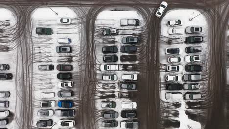Aerial-top-down,-cars-parked-in-snowy-parking-lot-during-winter-season