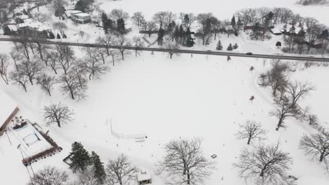 Aerial,-empty-snow-covered-field-in-neighborhood-community-park-during-winter