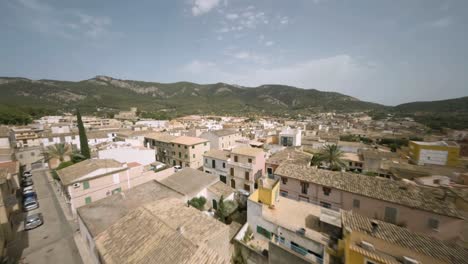 Drone-Aéreo-Fpv-Disparó-Sobre-Casas-E-Iglesia-En-Un-Casco-Antiguo-De-Andratx-Rodeado-Por-Una-Cordillera-En-Mallorca,-España-En-Un-Día-Soleado
