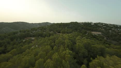 Aerial-drone-forward-moving-shot-downhill-the-green-mountain-range-at-daytime-Cala-d'Egos-beach-Mallorca,-Spain