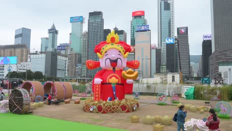 Leute-Machen-Fotos-Von-Einer-Themeninstallationsveranstaltung-Zum-Chinesischen-Neujahr-Im-Freien-Für-Das-Chinesische-Neujahrsfest,-Während-Wolkenkratzer-Im-Hintergrund-In-Hongkong-Zu-Sehen-Sind