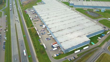 Warehouses,-huge-logistics-center-near-the-highway,-view-of-a-large-number-of-cargo-trailers-and-containers,-international-cargo-transportation,-aerial-view