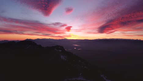 Silhouette-Luftaufnahme-Seitlich-Fliegen-Parallaxe-Efect-Während-Unglaublich-Farbenfrohen-Sonnenuntergang-Im-Winter-Mit-Schnee-Auf-Berggipfeln-In-Madrid,-Spanien