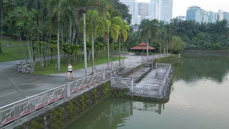 Young-woman-jogging-through-Perdana-botanical-gardens-in-Kuala-Lumpur,-Malaysia