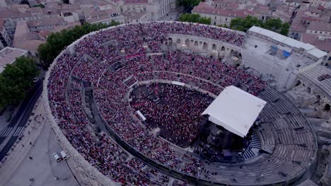 Drone-rotation-top-shot-over-the-Arena-of-Nimes-at-sunset,-people-are-waiting-for-the-stromae-concert