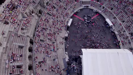 Drone-over-the-Arena-of-Nimes-at-sunset,-people-are-waiting-for-the-stromae-concert