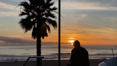 Man-watching-phone-at-sunset-near-the-beach