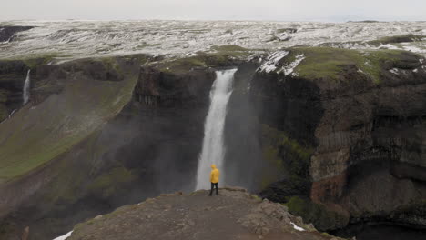 Aerial:-Flyover-one-person-wearing-yellow-jacket,-looking-at-Haifoss-waterfall