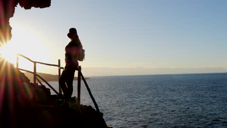 Wunderbare-Aufnahme-Einer-Jungen-Frau-Mit-Hut,-Die-Während-Des-Sonnenuntergangs-Die-Landschaft-An-Der-Küste-Der-Gemeinde-Galdar-Auf-Der-Insel-Gran-Canaria-Und-Während-Des-Sonnenuntergangs-Bewundert