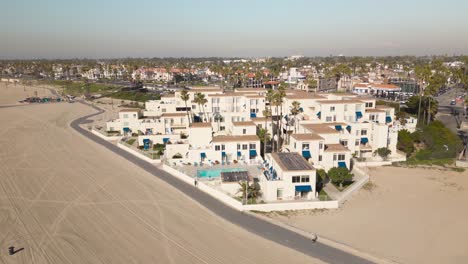 Huntington-Pacific-Beach-House-Condo-complex-in-this-beautiful-drone-time-lapse,-capturing-a-bright-sunny-day-with-people-relaxing-on-the-beach
