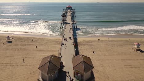 drone-video-captures-the-iconic-Main-Street-in-Huntington-Beach,-California-leading-into-the-Pacific-Ocean,-showcasing-the-famous-pier-and-lively-beach-atmosphere
