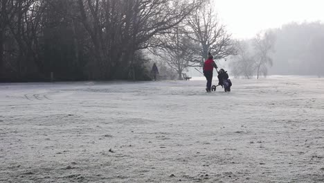London,-England---January-22-2023:-Golfers-walking-on-a-frost-covered-golf-course-in-winter