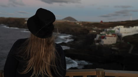 young-woman-with-a-hat-admires-the-landscape-and-cliffs-that-are-located-on-the-coast-of-the-municipality-of-Galdar-on-the-island-of-Gran-Canaria-and-during-sunset