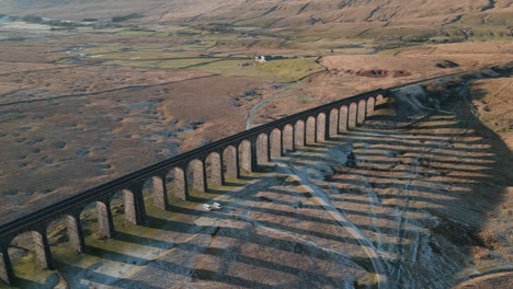 Railway-bridge-slow-partial-orbit-revealing-winter-moorland-with-long-shadows-at-Ribblehead-Viaduct