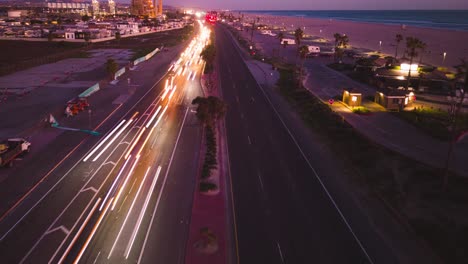 the-Pacific-Coast-Highway-in-Orange-County,-Huntington-Beach-during-sunset-in-this-breathtaking-drone-time-lapse,-showcasing-the-changing-colors-and-car-light-streaks