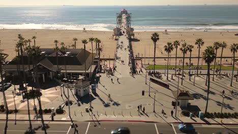 Stunning-drone-video-captures-the-iconic-Main-Street-in-Huntington-Beach,-California-leading-into-the-Pacific-Ocean,-showcasing-the-famous-pier-and-lively-beach-atmosphere