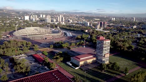 Aerial-shot-of-the-UNAM-Rectory,-behind-the-university-stadium-and-in-the-background-the-west-of-southern-Mexico-City-in-the-early-hours-of-the-morning