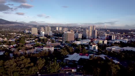 Aerial-shot-of-the-southern-outskirts-of-Mexico-City-near-Ciudad-Universitaria-at-sunrise-showing-several-buildings-of-various-types,-housing,-offices-and-shopping-malls