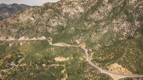 establish-drone-time-lapse-of-cars-on-winding-mountain-road-with-lush-greenery-in-the-Los-Angeles-National-Forest-and-small-settlements-in-the-valley