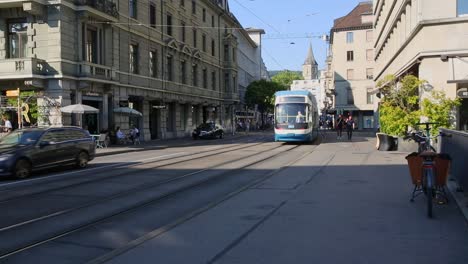 Tramway-passing-the-outdoor-cafe-tables-on-Zurich-main-street-on-sunny-day