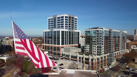 Bandera-Estadounidense-Ondeando-Frente-Al-Edificio-Del-Banco-De-América-En-El-Centro-De-Greenville,-Carolina-Del-Sur
