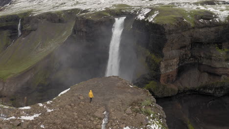 Aerial:-One-man-with-yellow-jacket-walking-towards-Haifoss-waterfall-in-Iceland