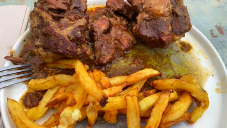 Traditional-Spanish-oxtail-stew-with-french-fries,-slow-cooked-meat-in-red-wine-sauce-in-Malaga-area-Spain,-4K-shot