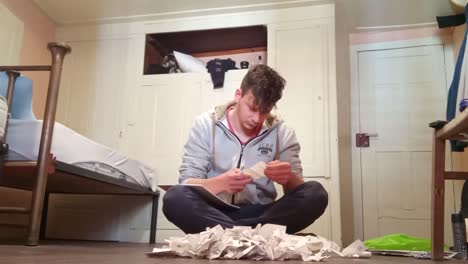 Young-man-calculating-expenses-adding-up-receipts-pile