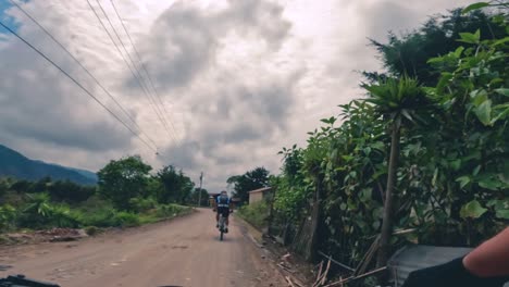 Zwei-Radfahrer-Fahren-Mit-Ihrem-Fahrrad-Auf-Einer-Straße-Innerhalb-Eines-Waldes,-Hügels-Und-Dorfes-In-Guatemala,-Nordamerika
