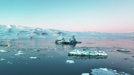Blue-Icebergs-Floating-in-Glacier-Lagoon-Jokusarlon-in-Iceland-during-Sunrise---aerial-drone-shot
